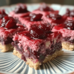 Cherry Mash Bars with a creamy cherry nougat base and a chocolate-peanut topping, cut into squares and arranged on a rustic wooden board.