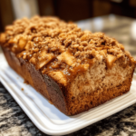 Peanut Butter Apple Streusel Bread with a golden streusel topping, sliced to reveal swirls of peanut butter and chunks of apple, served on a rustic wooden board.