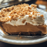 No-Bake Butterscotch Pie with a golden graham cracker crust, creamy butterscotch filling, and whipped cream topping, garnished with toffee bits on a decorative plate.