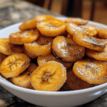 Sugar-Free Air Fryer Banana Chips, golden and crispy, arranged in a bowl with fresh banana slices for garnish, showcasing a healthy snack option.